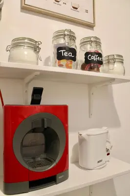 a red microwave on a shelf with jars and a cup at Ti Maria Guest House in Faro