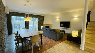 a dining room and living room with a table and a couch at Mosqueira by Check-in Portugal in Albufeira