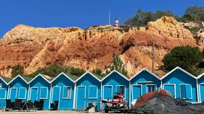 a group of blue beach huts in front of a mountain at Mosqueira by Check-in Portugal in Albufeira