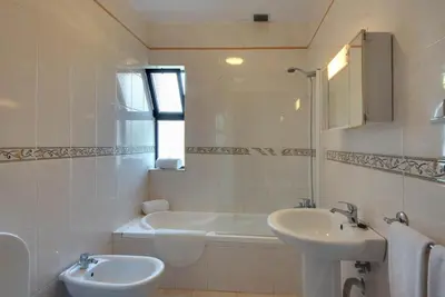 a white bathroom with a sink and a bath tub at Villa Coelho in Albufeira