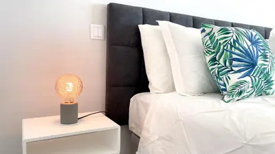 a bed with white pillows and a lamp on a night stand at Alvorada Premium by Sunny Deluxe in Albufeira