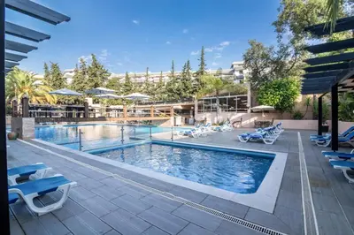 a swimming pool with blue chairs and a building at Apartamento Patrick by Sunnyway in Albufeira