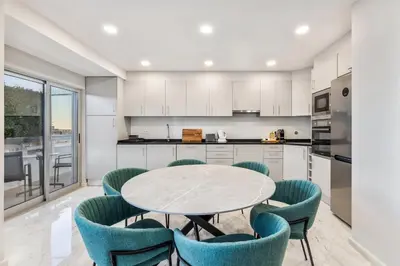a kitchen with a table and blue chairs at Faro Main Avenue Apartment in Faro