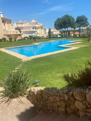 a swimming pool in a yard with a stone wall at Sweet Garden by SpotOn Apartments in Albufeira