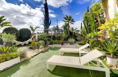 a garden with two white chairs and plants at Vila Rafa in Albufeira