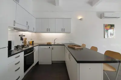 a kitchen with white cabinets and a black counter top at Vila Rafa in Albufeira
