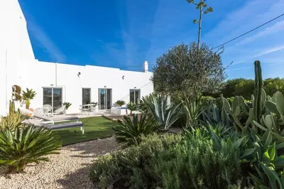 a white house with plants in the yard at Vila Rafa in Albufeira