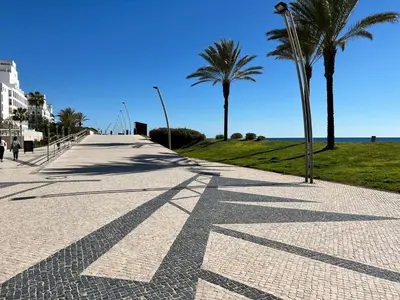 a sidewalk with palm trees on the side of a beach at Terraços Quarteira 2D3 in Quarteira