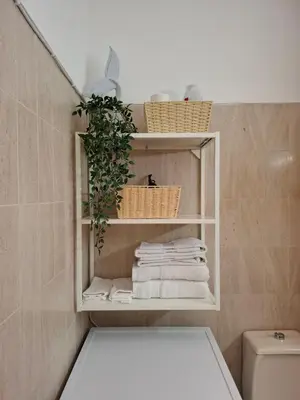 a bathroom with white towels and baskets on shelves at Title e Title - Oura Apartament Albufeira in Albufeira