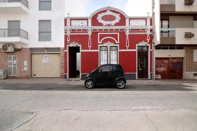 a small car parked in front of a red building at Casa Vermelha ii in Faro