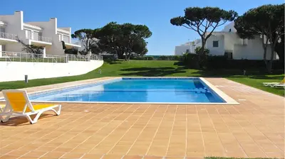 a swimming pool with a chair next to a house at Villa Terraços da Vinha 230 - Clever Details in Vilamoura