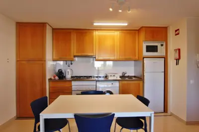 a kitchen with wooden cabinets and a table and chairs at Lago Azul Apartment II in Quarteira