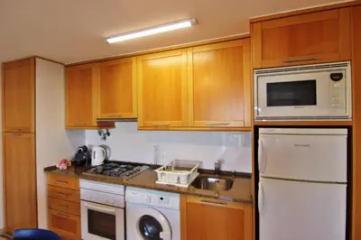 a kitchen with wooden cabinets and a white appliance at Lago Azul Apartment II in Quarteira