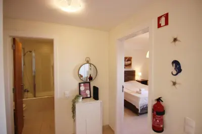 a bathroom with a mirror and a bedroom with a bed at Lago Azul Apartment II in Quarteira