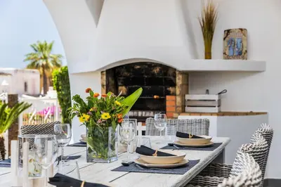 a table with plates and flowers in a vase at Villa Eva by OCvillas in Albufeira