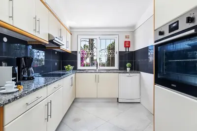 a kitchen with white cabinets and a window at Villa Eva by OCvillas in Albufeira