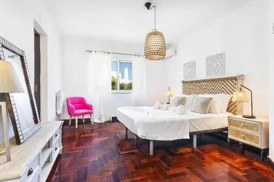 a white bedroom with a bed and a red chair at Villa Eva by OCvillas in Albufeira