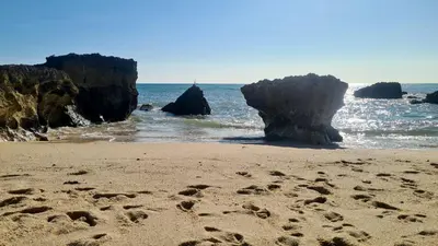 a beach with rocks and footprints in the sand at Albufeira Balaia Mar e Sol in Albufeira