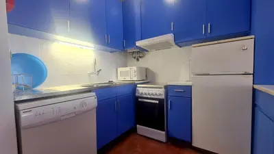 a blue kitchen with white appliances and blue cabinets at Albufeira Balaia Mar e Sol in Albufeira