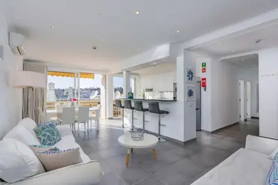a living room with a white couch and a kitchen at Old Town Beach Apartments in Albufeira