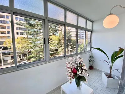 a room with windows and a vase of flowers on a table at Cosy Avenida Apartment in Faro