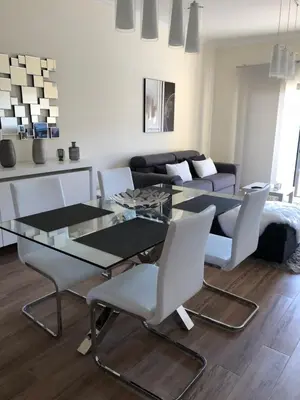 a dining room with a glass table and white chairs at MARINA BLEU Magnifique Appartement Standing vue Piscine in Albufeira