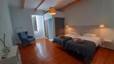 a bedroom with two beds and a blue chair at A Casa do Tenente in Faro