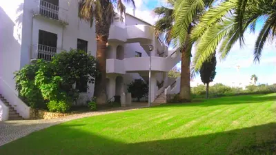 a white building with palm trees in front of it at Vue mer et piscine à 5 min à pied de Praia Sao Rafael Albufeira in Albufeira