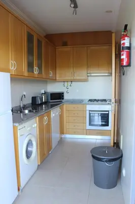 a kitchen with wooden cabinets and a washer and dryer at Casa Jacqueline in Albufeira