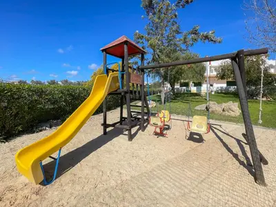 a playground with a slide and chairs in a park at Cozy Townhouse Vila Rafaella near São Rafael Beach Albufeira in Albufeira