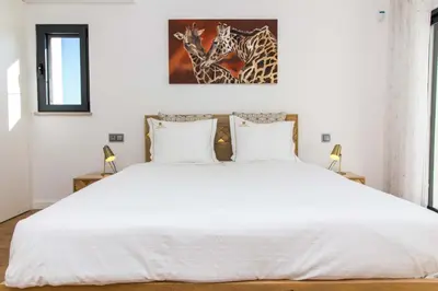 a bedroom with a white bed with two giraffes on the wall at Villa Videira By Dalma Portuguesa - By Dalma Portuguesa in Albufeira