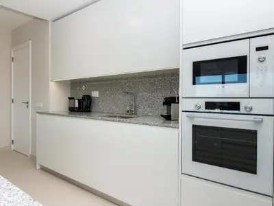 a white kitchen with a stove and a microwave at Green 2 Apartment by Stay ici Algarve Holiday Rental in Albufeira