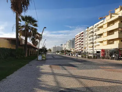 an empty city street with palm trees and buildings at T3 Alto Forte -Vista Mar,Ar Condicionado,Garagem in Quarteira