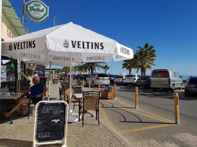 a person sitting at a table under an umbrella at T1 BOAVISTA 6 VISTA MAR Wi-Fi Ar Cond in Quarteira