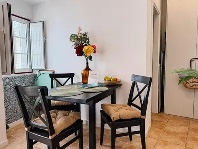 a dining room table with chairs and a vase with flowers at Old Fisherman's Corner 5 - Centro Old Town Albufeira in Albufeira