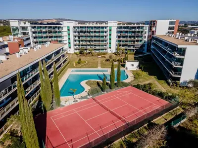 two beds in a room with a window at Superbe appartement spacieux avec terrasse vue piscine in Vilamoura