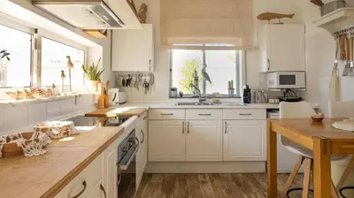 a kitchen with white cabinets and a wooden table at Villa O Canto da Parra - Hot Jacuzzi - Swimming Pool - WIFI - BY BEDZY in Galé