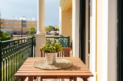 a wooden table with a potted plant on a balcony at São João das Areias By Albufeira Rental in Albufeira