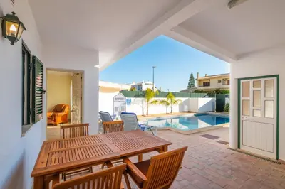 a patio with a wooden table and chairs and a pool at Villa Sequeira - Private Pool - Free WIFI - BY BEDZY in Albufeira