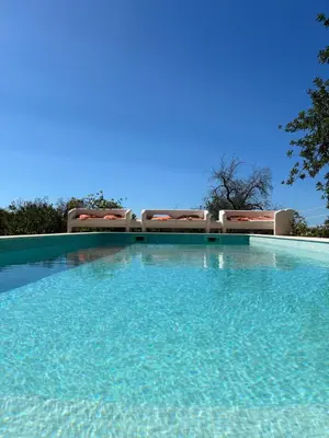 a large swimming pool with chairs and blue sky at Einzigartige Landhaus-Villa mit Pool, Sauna, Bar und BBQ in Boliqueime