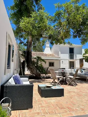 a patio with a couch and chairs and a tree at Stilvolles Architekten-Cottage mit Pool in Boliqueime