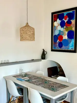 a glass table with white chairs and a painting at Stilvolles Architekten-Cottage mit Pool in Boliqueime