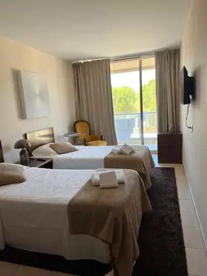 a hotel room with three beds and a window at Salgados, Vila das Lagoas in Albufeira
