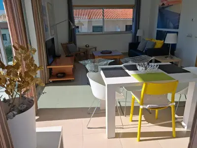 a living room with a white table and yellow chairs at Modern apartment with sunny south facing terrace in Albufeira