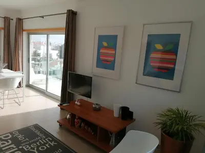 a living room with a flat screen tv and a table at Modern apartment with sunny south facing terrace in Albufeira