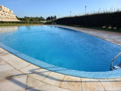 a large swimming pool with blue water at Prestige & Nature Apartment in Laguna Village in Quarteira