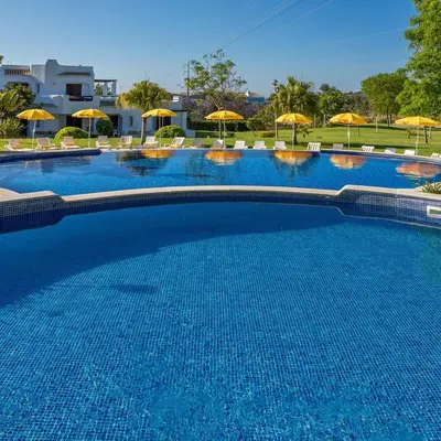 a large blue swimming pool with chairs and umbrellas at Amazing 2-Bedroom Appartment with big terrace! in Albufeira