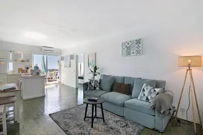 a living room with a blue couch and a kitchen at Ocean View Apartment Hakuna Matata in Albufeira
