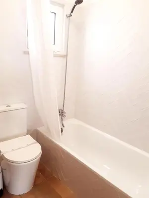 a white bathroom with a toilet and a bath tub at Beach Apartment Terrace in Vilamoura