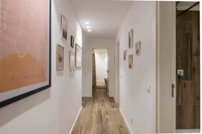 a hallway with white walls and wood floors and pictures at Downtown Albufeira 3-Bedroom Luxury Apartment in Albufeira